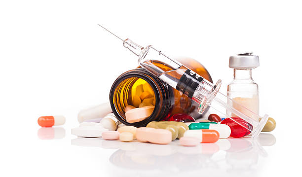 image1 Pills spilled from a brown prescription bottle with a syringe and vials on a white surface, indicating medication use or administration.