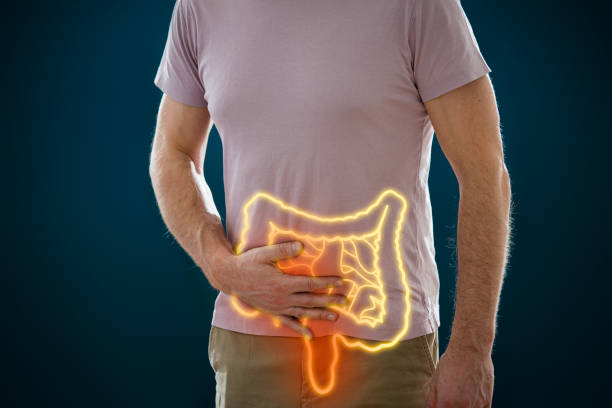 Person holding their abdomen with a glowing outline of the digestive tract (intestines) overlaid on their midsection.