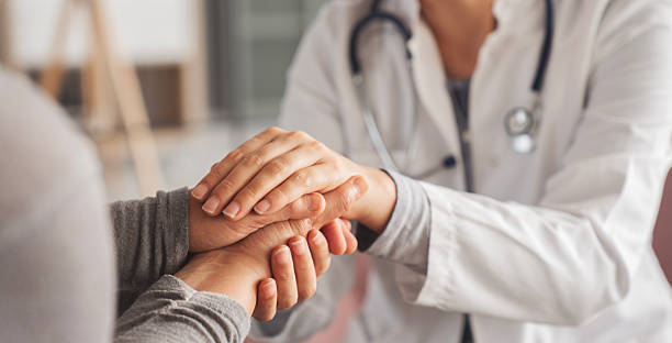 Doctor in white coat offering supportive hand-holding to a patient, conveying care and reassurance in a clinical setting